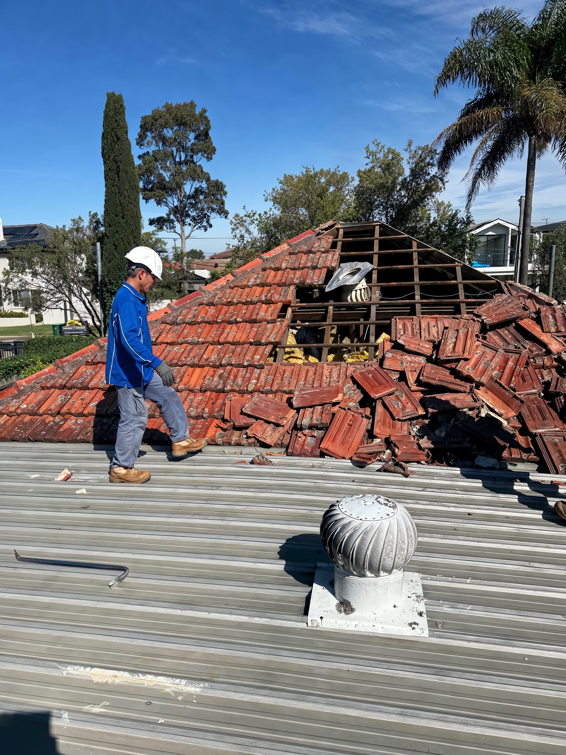 Worker removing roof tiles